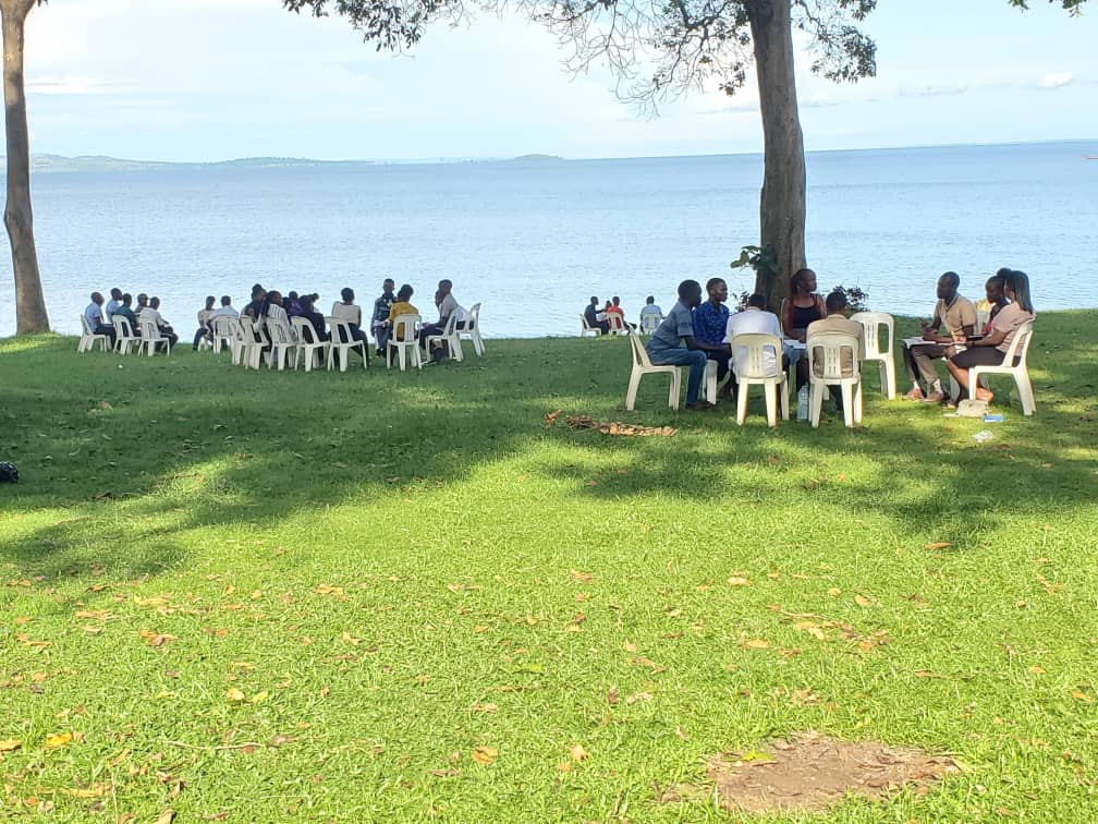 Students in small discussion groups on the lawn at the FOCUS campsite, with Lake Victoria behind them