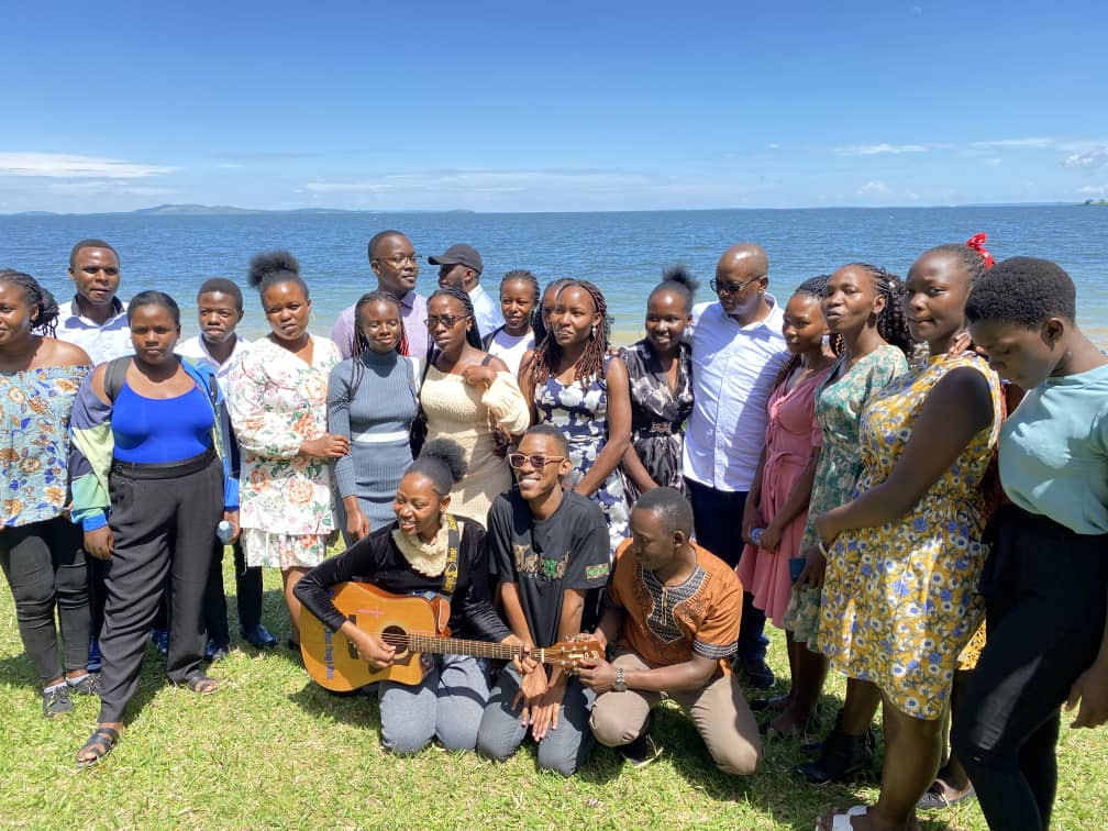 A group singing together with a guitar on the shore at the FOCUS Campsite
