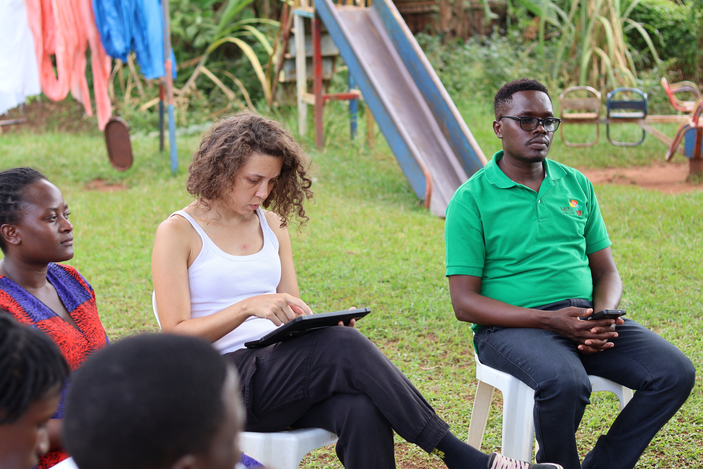 STEM staff seated outdoors during a session, one taking notes on a tablet